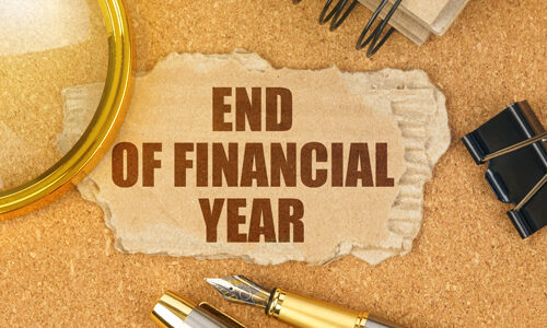On the table are office items and a cardboard with the inscription - END OF FINANCIAL YEAR